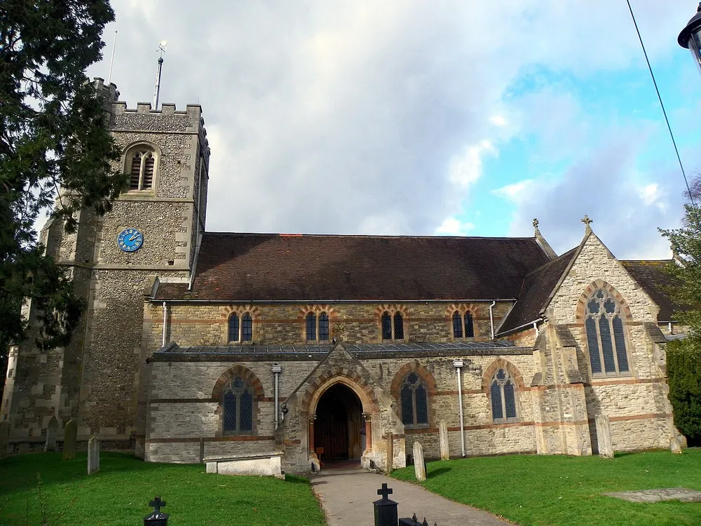 The flint tower of St Nicholas Church rising above the trees in Harpenden