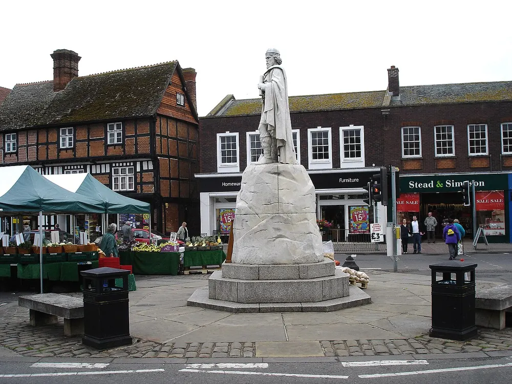 The white stone statue of King Alfred the Great on its plinth in Wantage Market Place, market stalls behind